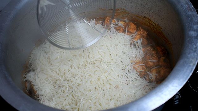 Paneer Biryani Recipe Restaurant Style Take rice from water and put it in Paneer Biryani Recipe to form layer.